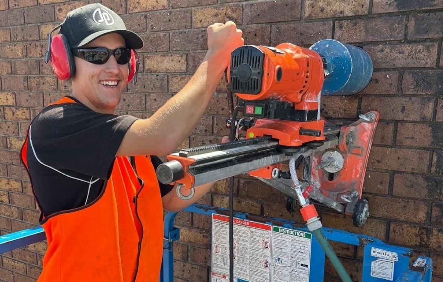 Worker in high-visibility vest operates a core drilling machine.