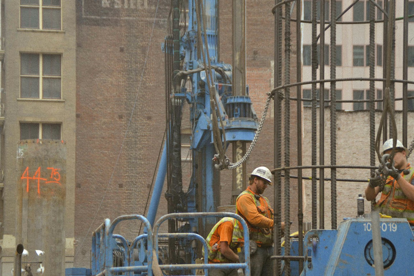 Construction workers operating heavy machinery on a large building project.