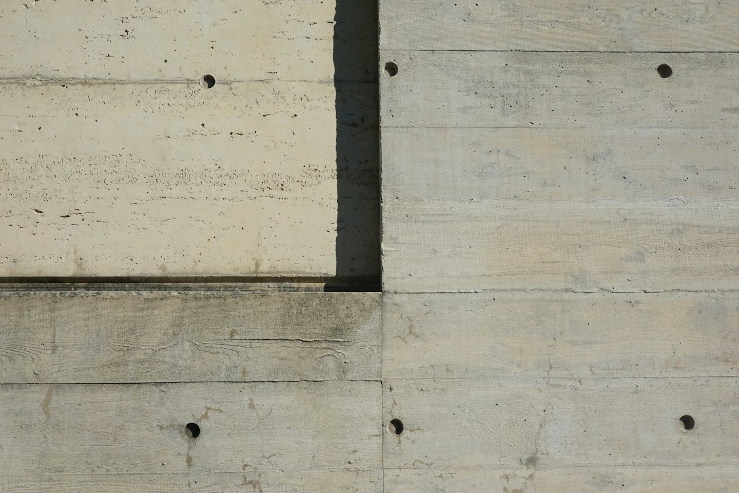 Board-formed concrete wall with wood grain texture and tie holes.